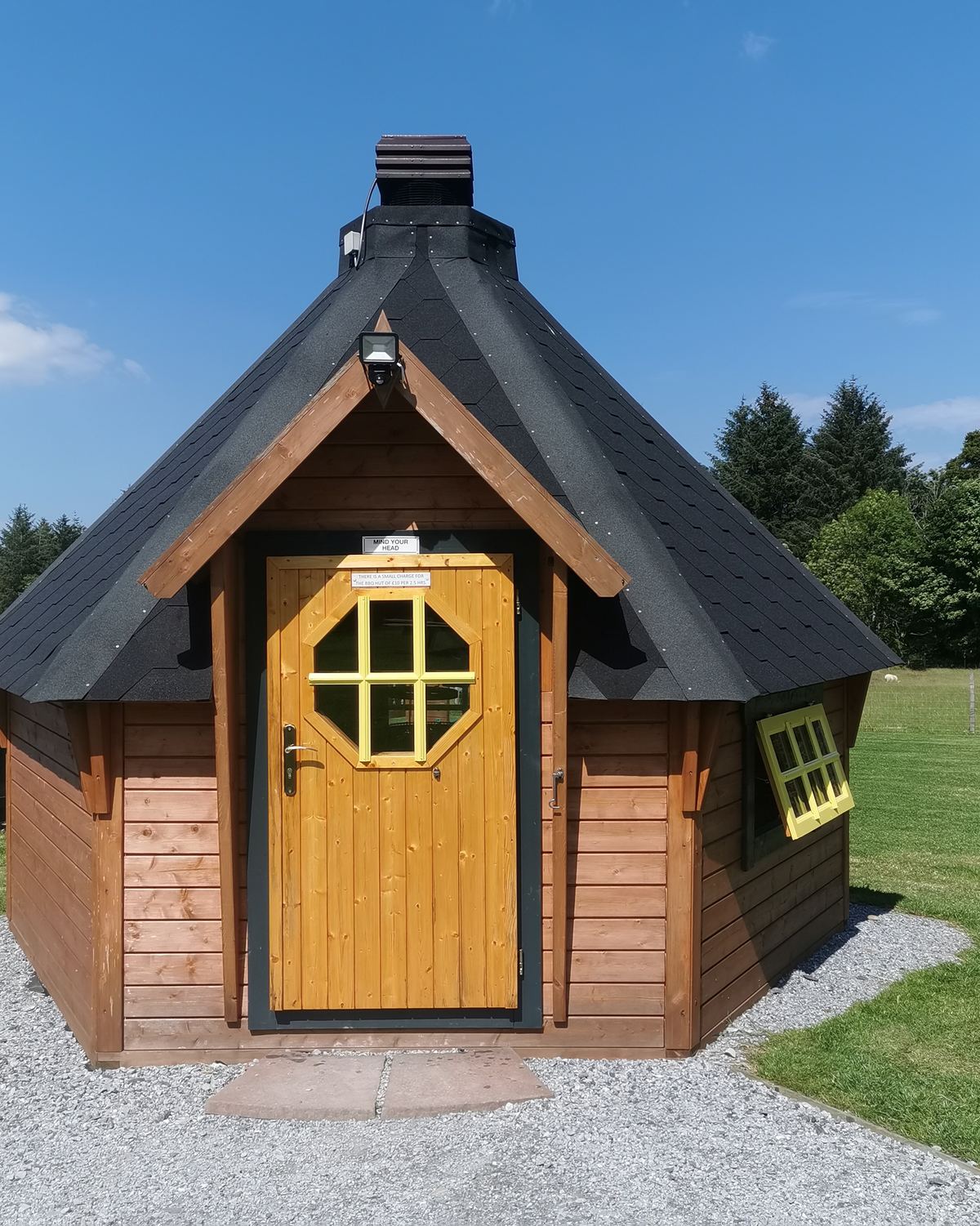 The dark timber barbecue hut with its round window at Greencraig