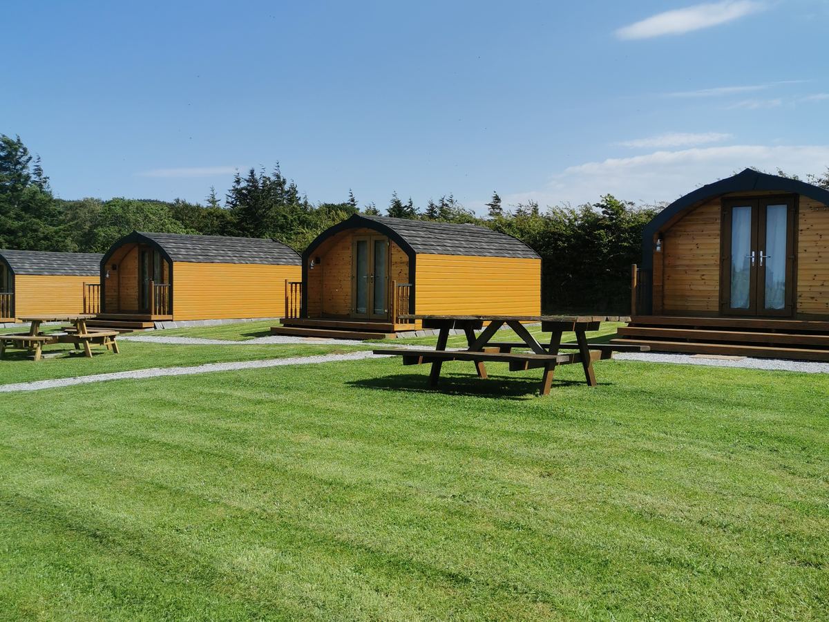 Greencraig glamping pods with their picnic benches on the lawn